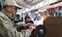 Uşak Mende Pazarı'ndaki çınarın altında kurban önü çalışan Nurettin Aydın'ın bilediği bıçakla ense tıraşı yapılıyor