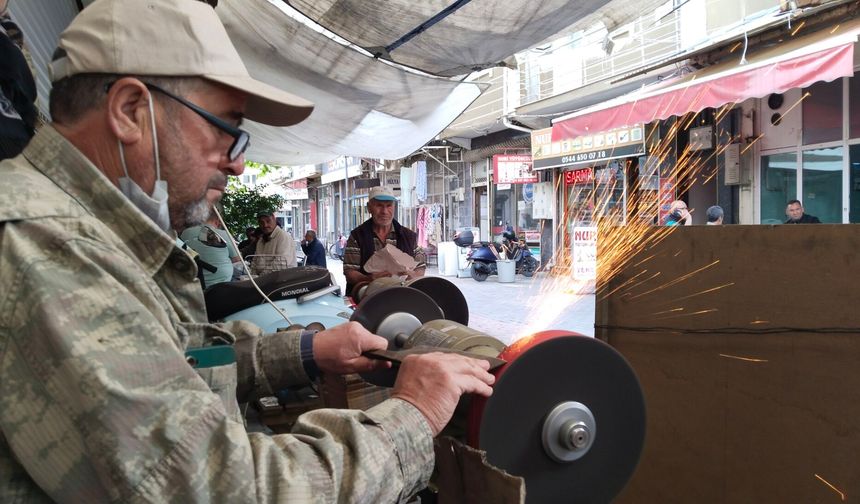 Uşak Mende Pazarı'ndaki çınarın altında kurban önü çalışan Nurettin Aydın'ın bilediği bıçakla ense tıraşı yapılıyor